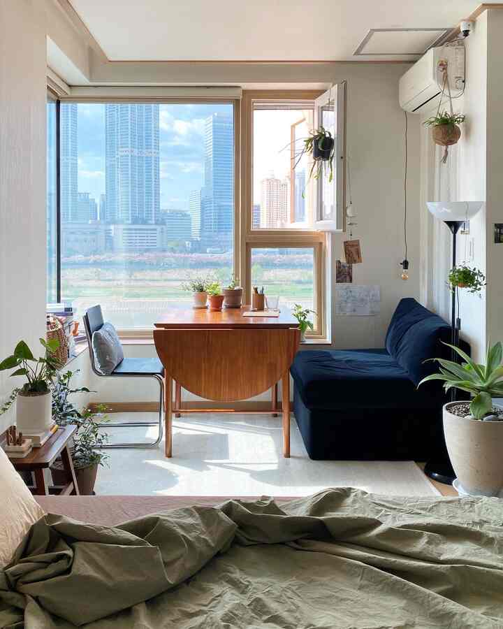 ナチュラルな色調のリビング空間、木製ダイニングテーブルとネイビーのソファが配置された光あふれる落ち着いたインテリア