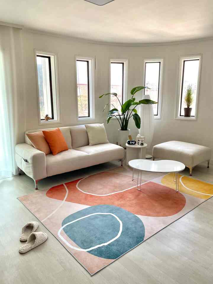 Ivory and brown toned living room featuring a beige sofa, colorful rug, and greenery in a natural modern style interior
