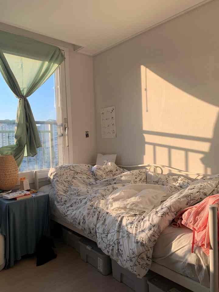 Cozy studio bedroom in warm natural tones featuring floral duvet and storage boxes under bed