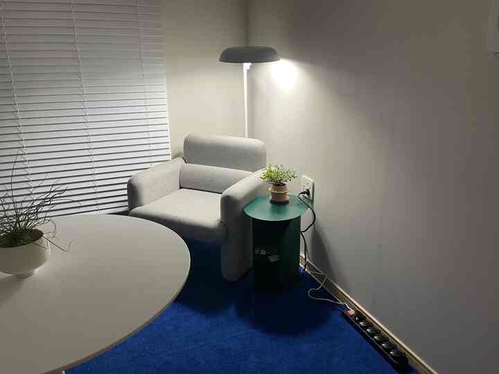 Small living room in white and gray tones featuring a gray armchair and green side table, creating a modern and cozy atmosphere