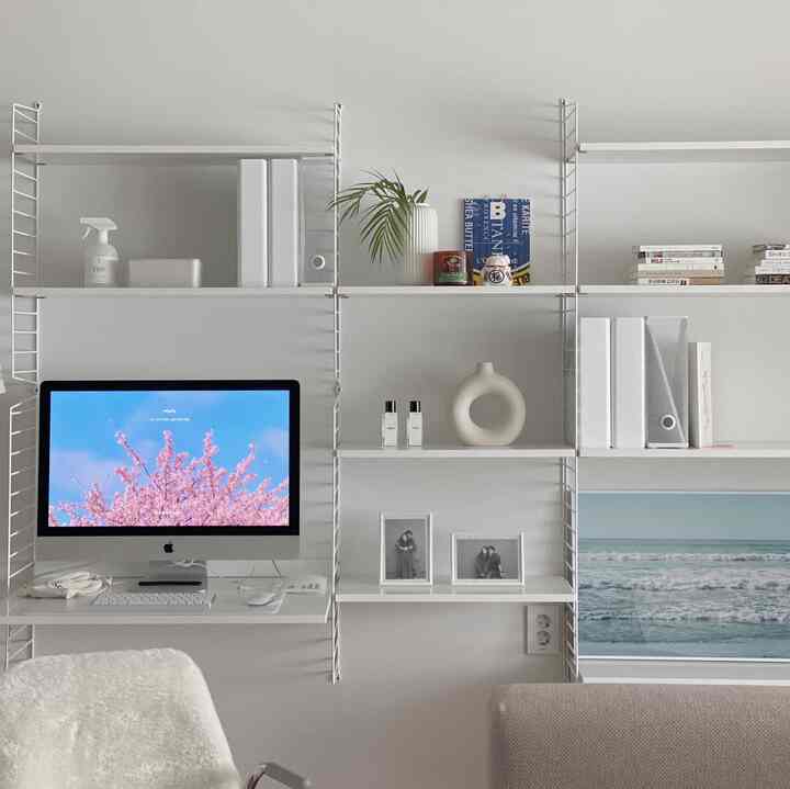 White-toned Nordic style home office space featuring system shelves and a computer desk with clean decor