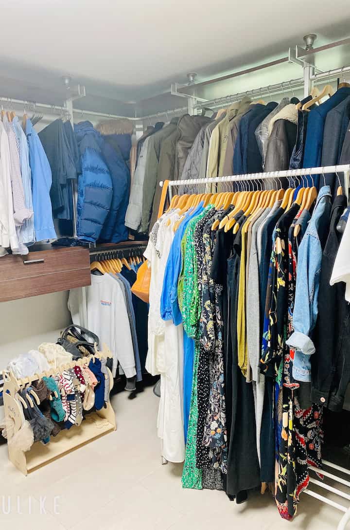 白と木目調が調和したウォークインクローゼット、システムハンガーに多様な服が整頓された清潔な空間