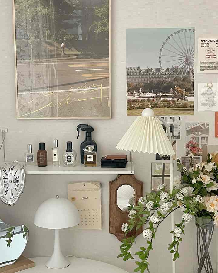 白とナチュラルな色調のワンルーム、壁棚とポスター、植物と照明が配置された雰囲気のあるインテリア