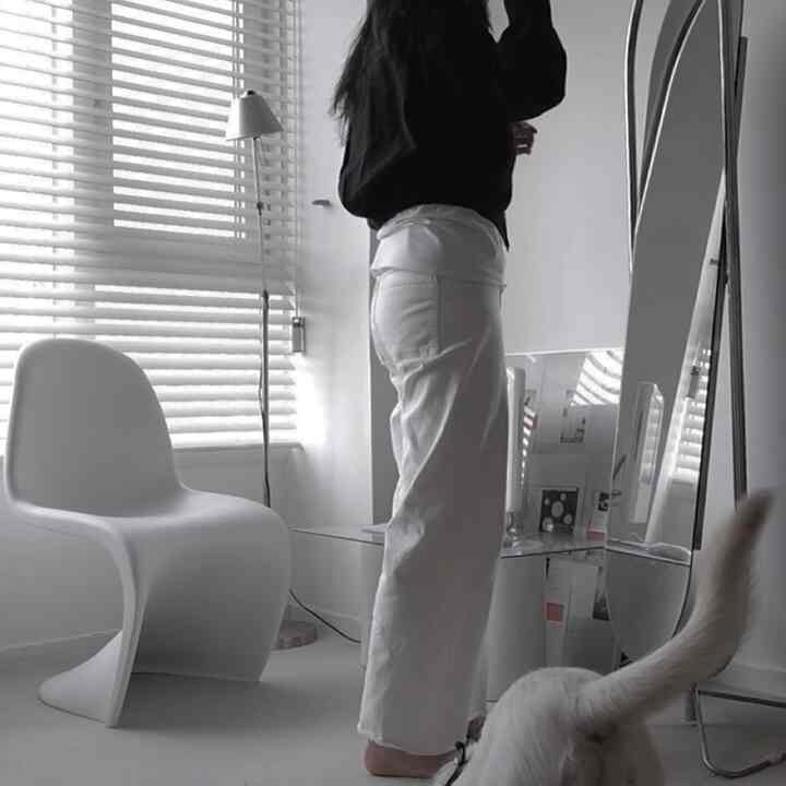 白を基調としたワンルーム、窓際にブラインドと白い椅子、全身鏡と机が配置されたシンプルな空間