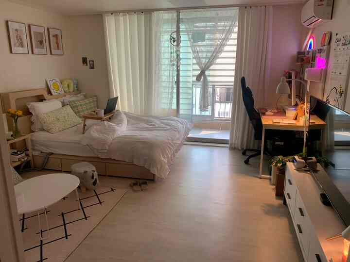 White and wood-toned studio bedroom with home office area, cozy and neat atmosphere