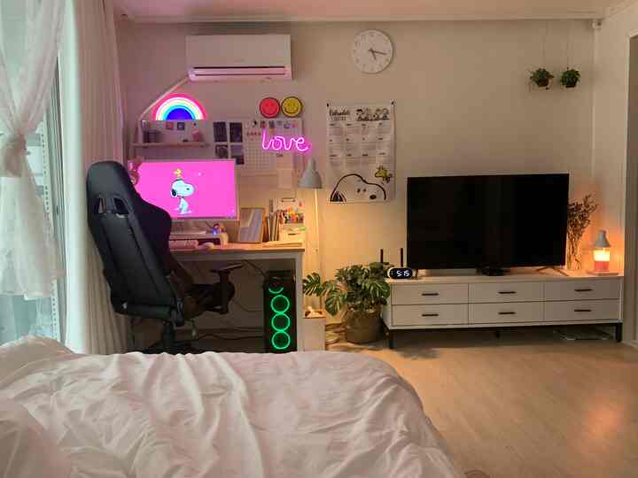 White and beige toned bedroom and home office featuring neon sign lighting and a gaming chair creating a cozy, modern atmosphere
