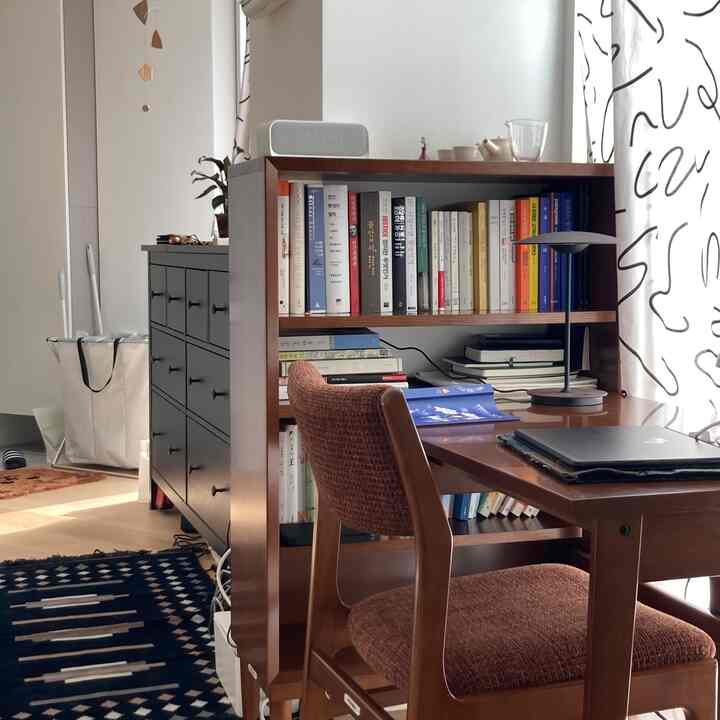 Natural brown wood tone compact home office with black accents, featuring a bookshelf, desk, and chair in a cozy atmosphere