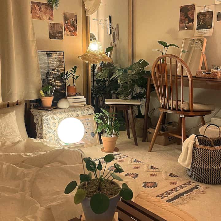 Warm beige bedroom space featuring wooden chair, desk, various plants, and soft lighting creating a cozy interior
