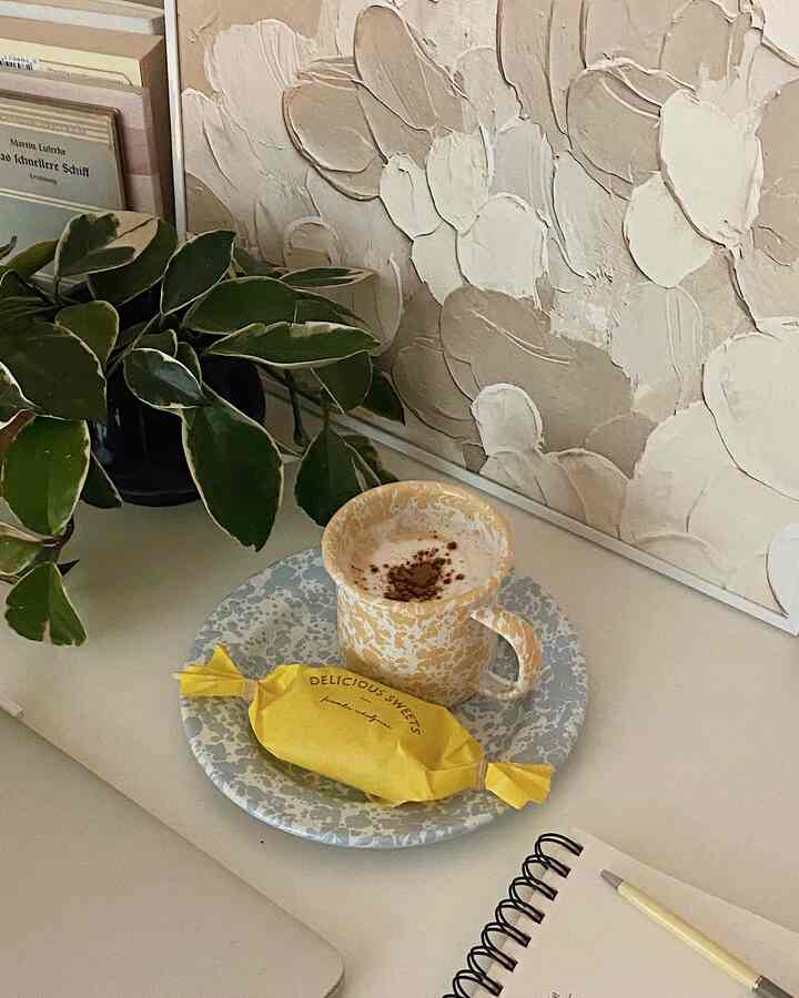 Natural tones desk featuring a mug, plate, and plant creating a cozy home cafe atmosphere