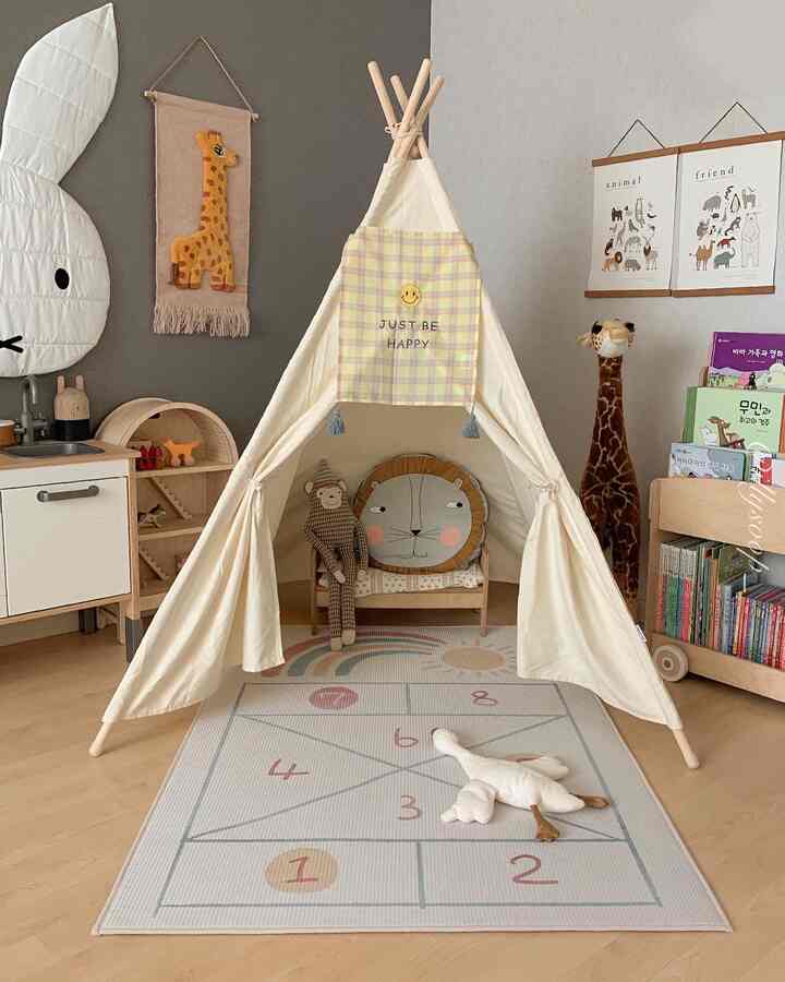 Natural toned kids' room featuring a central Indian tent and child-sized furniture creating a cozy play area