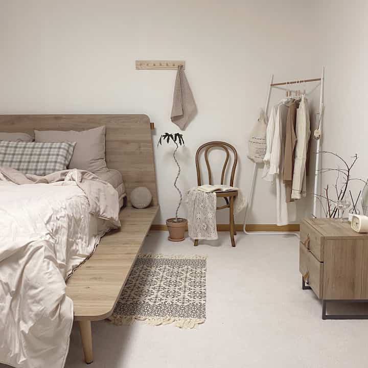 ナチュラルな色調の寝室、木製ベッドとナイトテーブルが配置された落ち着いた雰囲気のインテリア