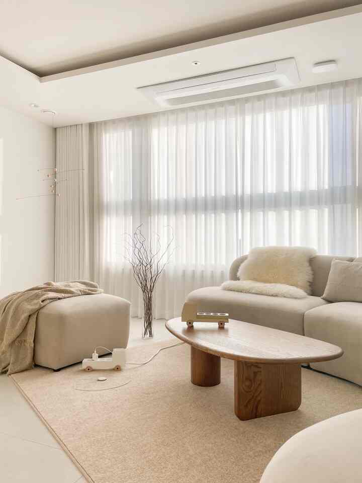 Bright white and beige toned living room featuring a wooden coffee table and beige sofa in a natural, minimal design