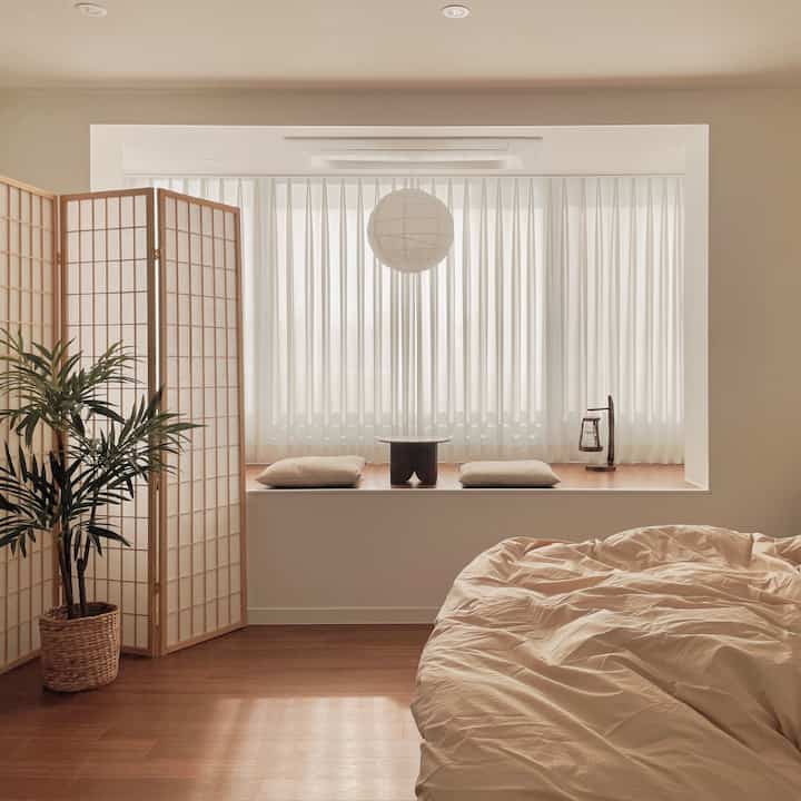 A natural-toned bedroom featuring beige bedding, a wood partition, and minimalist design creating a cozy atmosphere