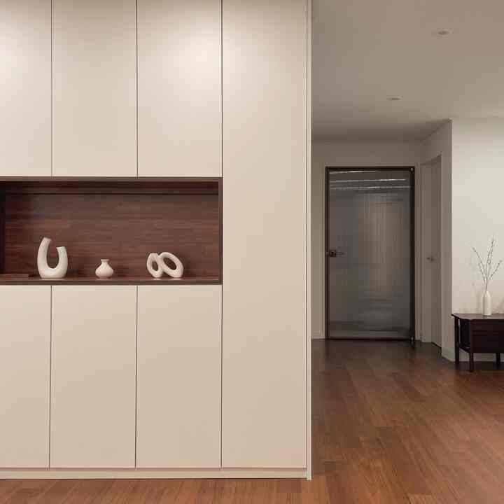 White and brown toned living room featuring built-in closet and wood interior objets with a minimal and natural atmosphere