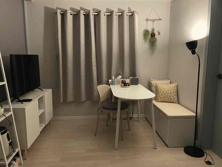 柔らかなベージュとホワイトのトーンの小さなリビング兼ダイニングルーム、モダンな家具とシンプルな照明が配された空間