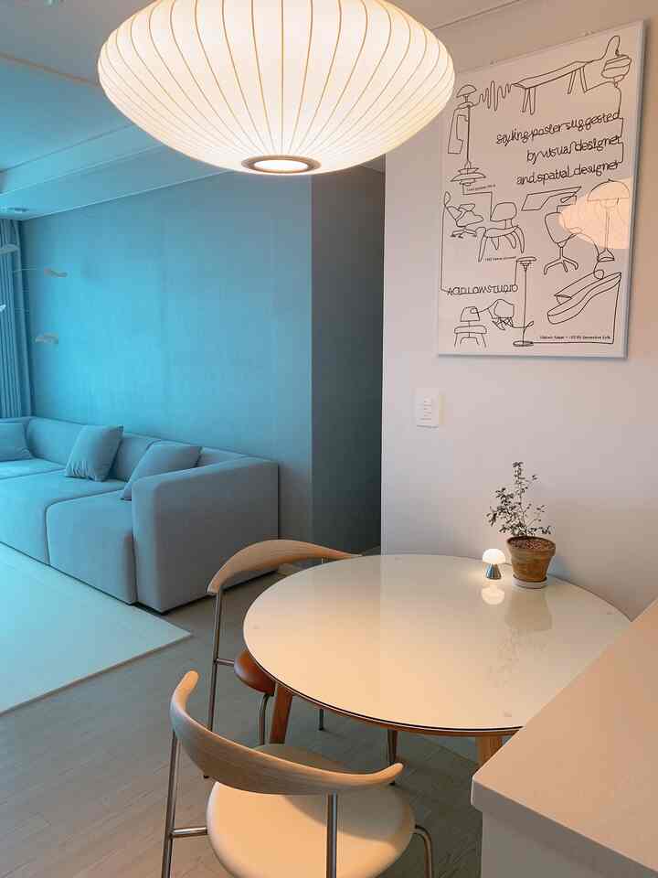 White and sky blue toned living and dining area featuring Mid-Century Modern furniture and plants in a clean setting