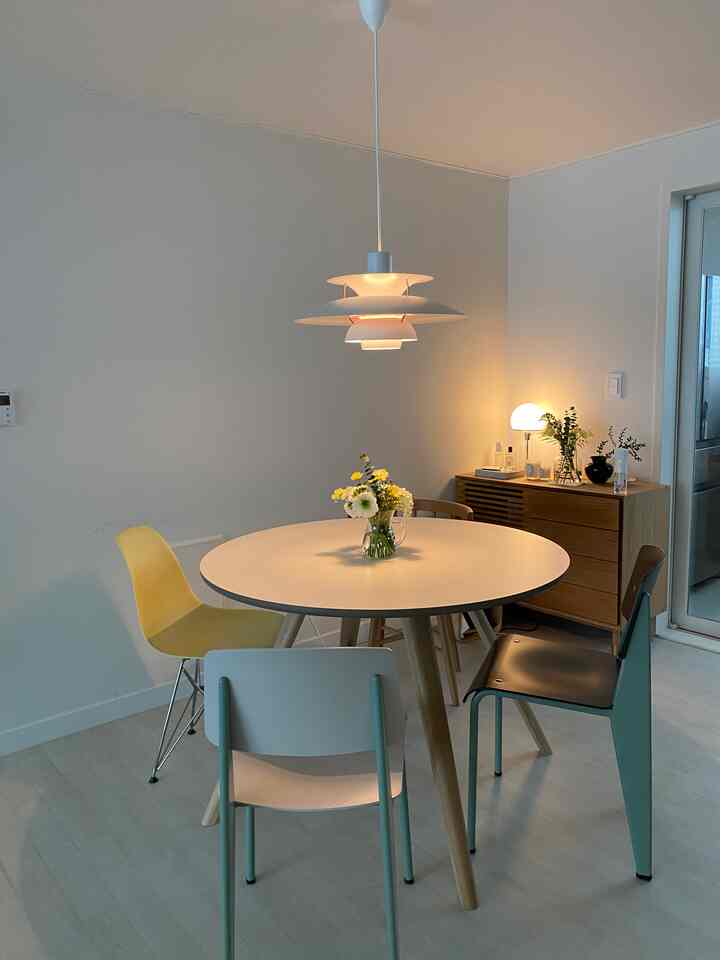 白と木目調のダイニング、丸いダイニングテーブルと様々な色の椅子が配置された雰囲気のある空間