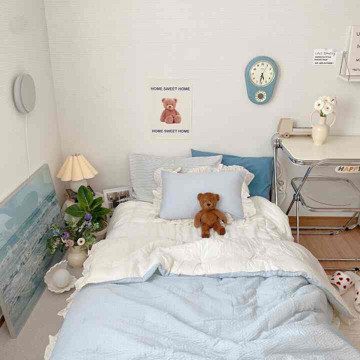 A cozy bedroom in soft beige and sky blue tones featuring a bed and desk neatly arranged for a natural modern feel