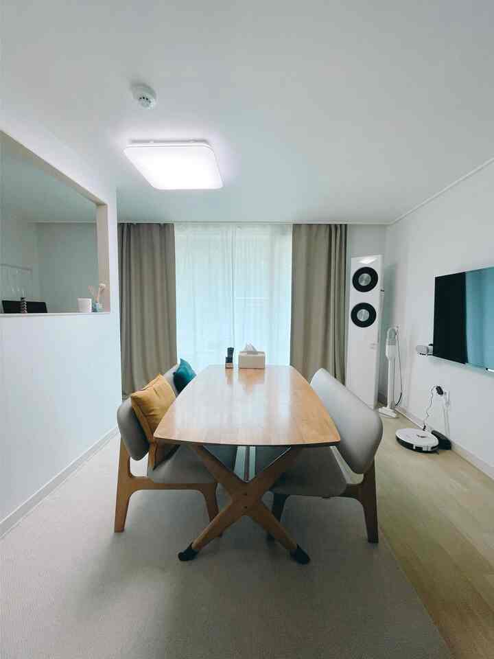 ナチュラルな木目調とベージュのカーテンが調和する4人用ダイニングルームとリビングスペース