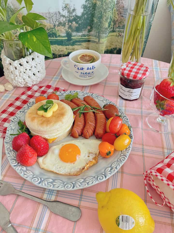 ピンクのテーブルクロスにブランチとお茶、植物が配置された温かみのあるナチュラルなホームカフェ空間