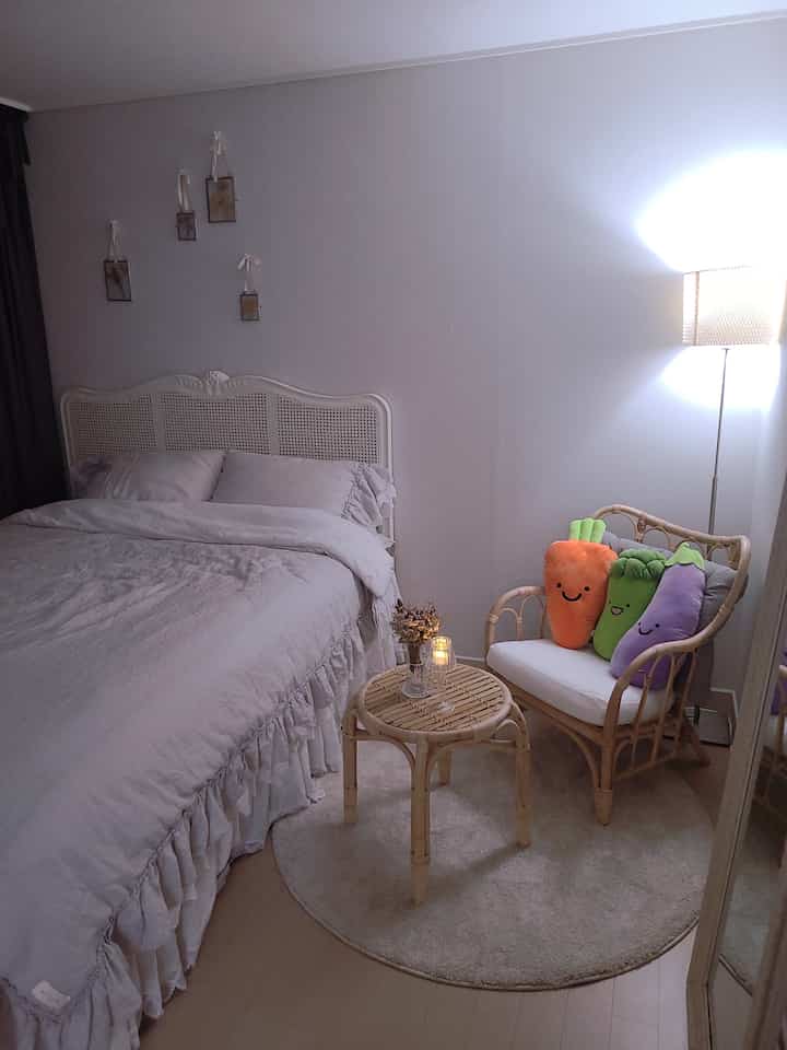 Natural beige-toned bedroom with rattan armchair and table, floor lamp creating cozy atmosphere