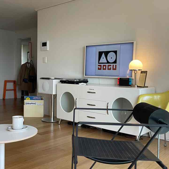 Modern living room in white and brown tones featuring a round-detailed storage cabinet and yellow armchair in a cozy setting