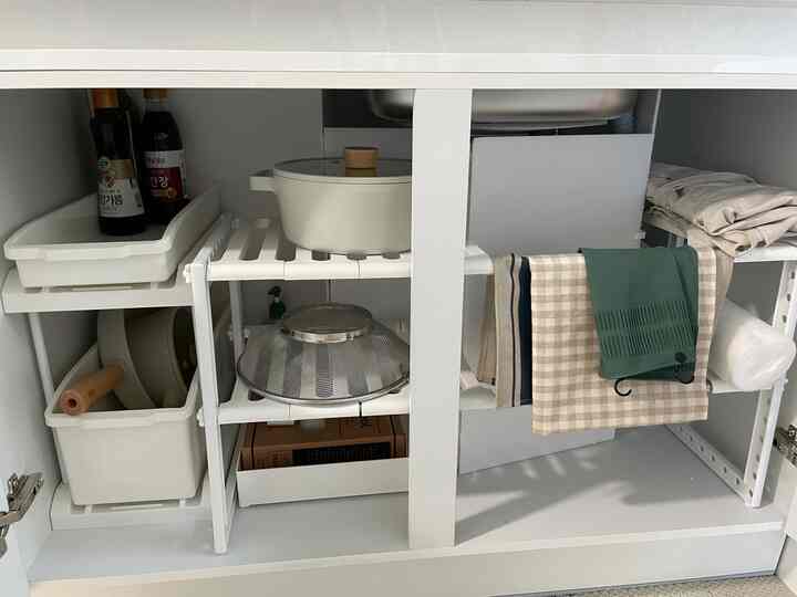 White kitchen cabinet interior featuring neatly organized shelves and kitchenware with a clean storage atmosphere