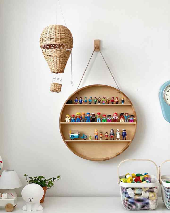 白い壁とナチュラルな木製の丸い棚がある子供部屋、おもちゃと小物が整頓された清潔な空間