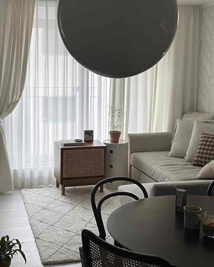 A living room in white and beige tones featuring a sofa, rug, and wooden furniture creating a cozy modern interior