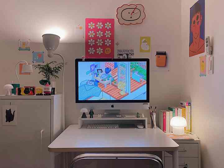 White-toned compact home office space featuring a monitor and lamps with a clean, modern work setup