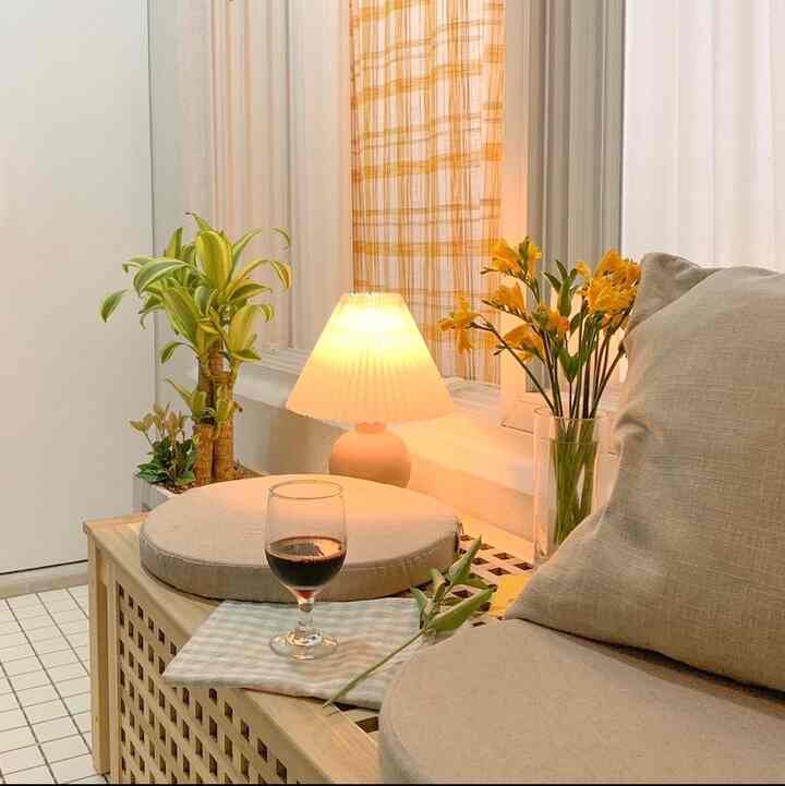 Warm wood tones and yellow accents in a veranda featuring cozy cushions and a wine glass, creating a relaxing atmosphere