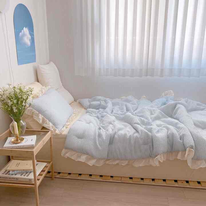 Ivory and light blue toned bedroom featuring a wooden bed frame and ruffled bedding creating a cozy atmosphere