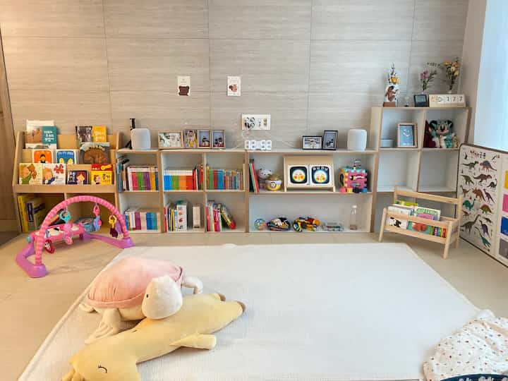 ナチュラルカラーの赤ちゃんと暮らすリビング、ベビーマットと絵本棚が配置された温かみのあるインテリア