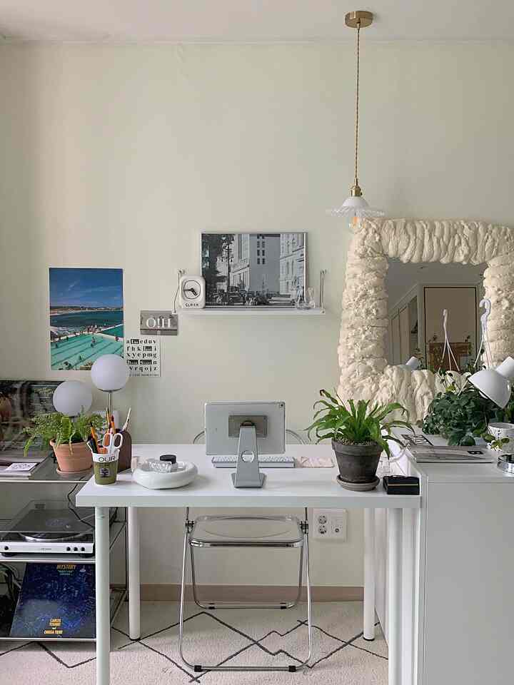 白を基調とした植物が映えるモダンなホームオフィス空間、机や調和の取れたレイアウトと小物が配置された印象的なインテリア