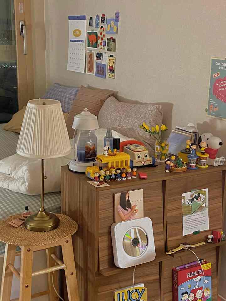 ブラウンとベージュのトーンのワンルーム寝室、ベッドとテーブルランプ、ヴィンテージの小物が配置された雰囲気のあるインテリア