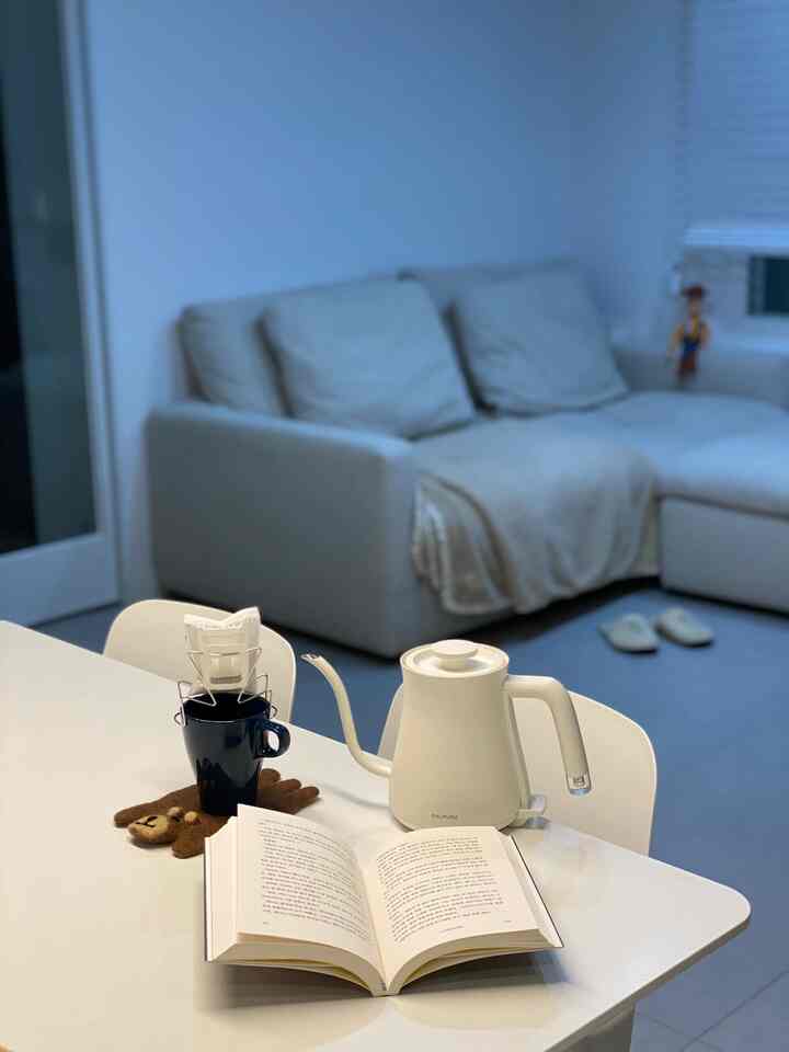 白と青の色調のリビング、白いテーブルにハンドドリップコーヒーセットと本が置かれた雰囲気のあるホームカフェ空間