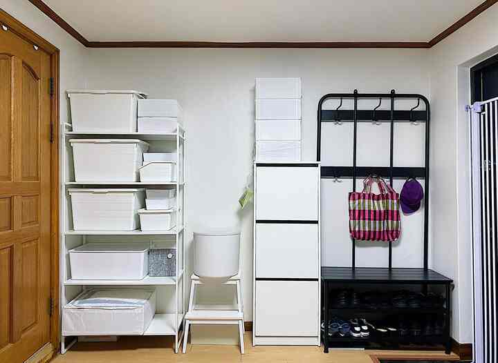 黒と白のトーンの玄関、整理された収納棚と靴箱が配置されたシンプルな空間