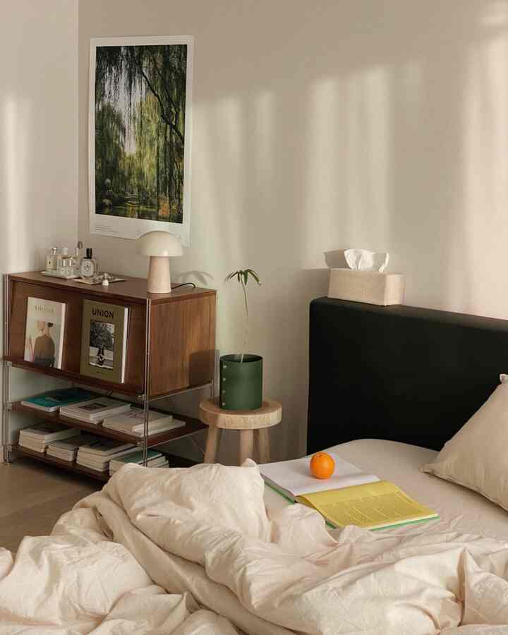 Soft beige-toned bedroom with wooden stool and dark bed frame, creating a cozy and natural atmosphere