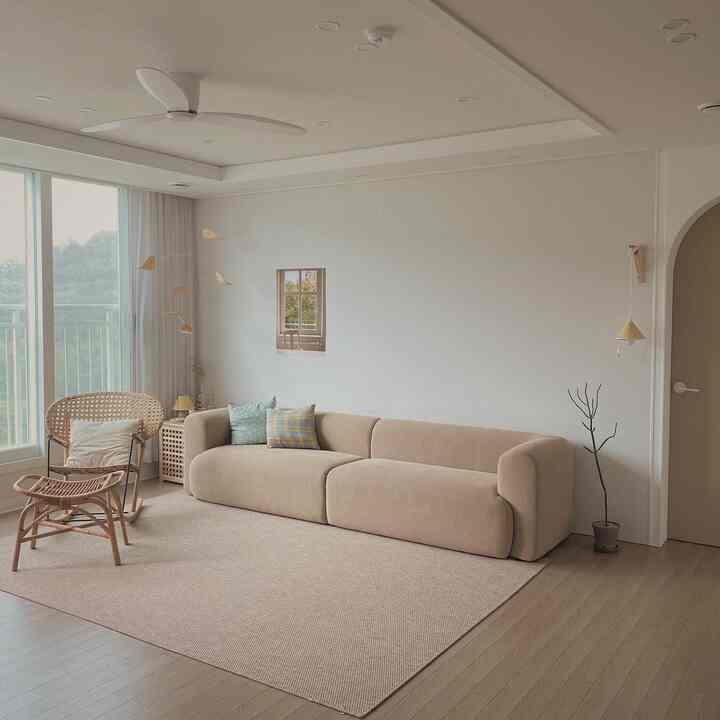 Natural beige-toned living room featuring a beige sofa, rattan rocking chair, and rug creating a simple and natural atmosphere