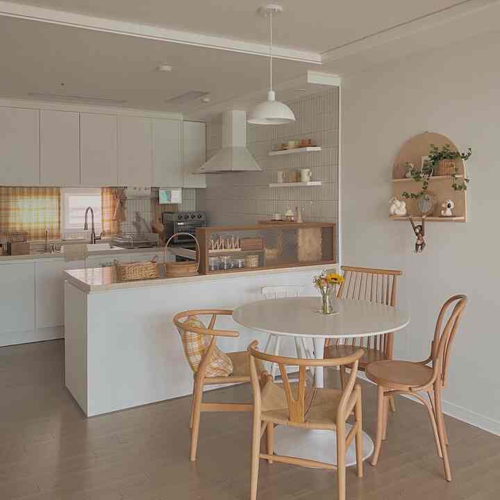 White and brown toned kitchen with a round dining table for four, featuring a warm and natural atmosphere