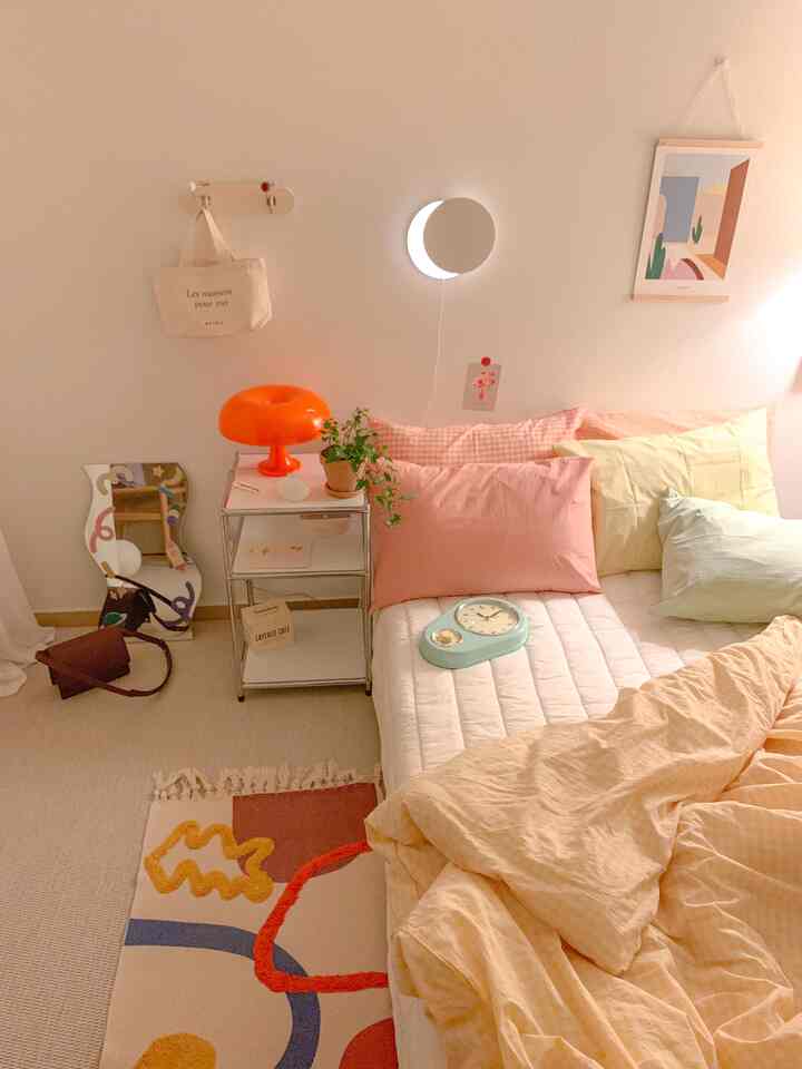 Soft beige and pastel-toned bedroom featuring a bed, side table, and crescent moon-shaped wall light creating a cozy atmosphere