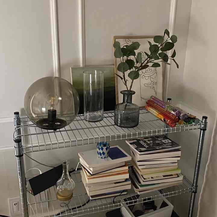 Nordic style space with white walls and gray metal shelves, featuring books, vases, and art frames in a clean interior