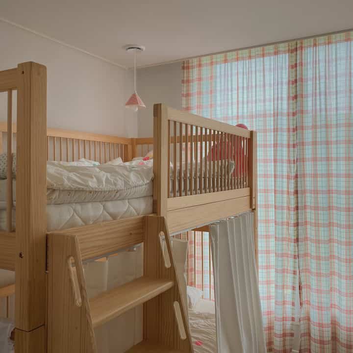 明るいナチュラルな木目調の子供部屋、木製二段ベッドとチェック柄カーテンが落ち着いた雰囲気を作る空間