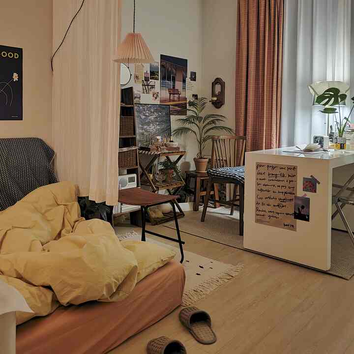 Beige and wood tone studio bedroom featuring cozy bedding, wooden chairs, and various plants in a natural modern interior