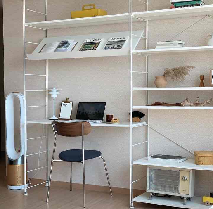 ベージュトーンの壁と木目調の床に、ホワイトのモジュラー家具とデスク、ブラウンの椅子が配置された印象的な書斎空間