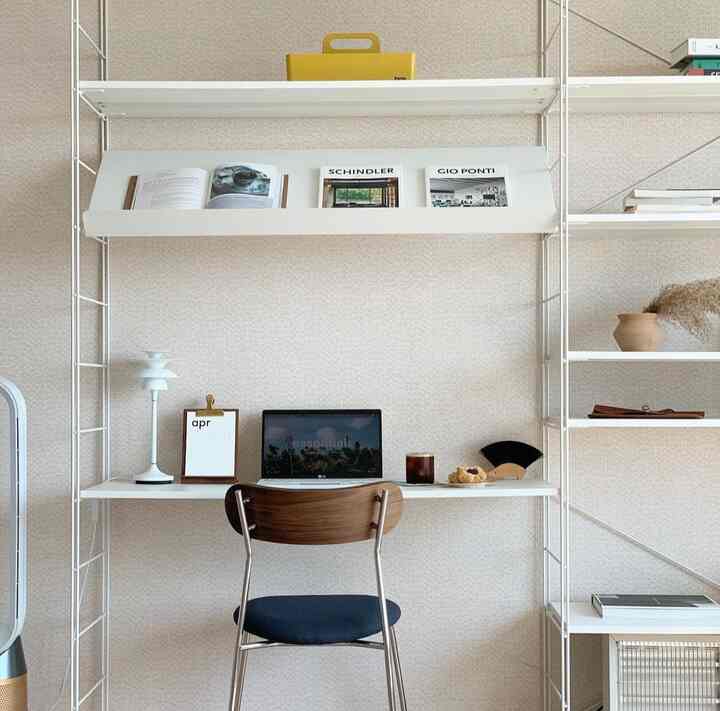 Bright ivory walls and white shelves with a wood-tone chair in a compact home office space