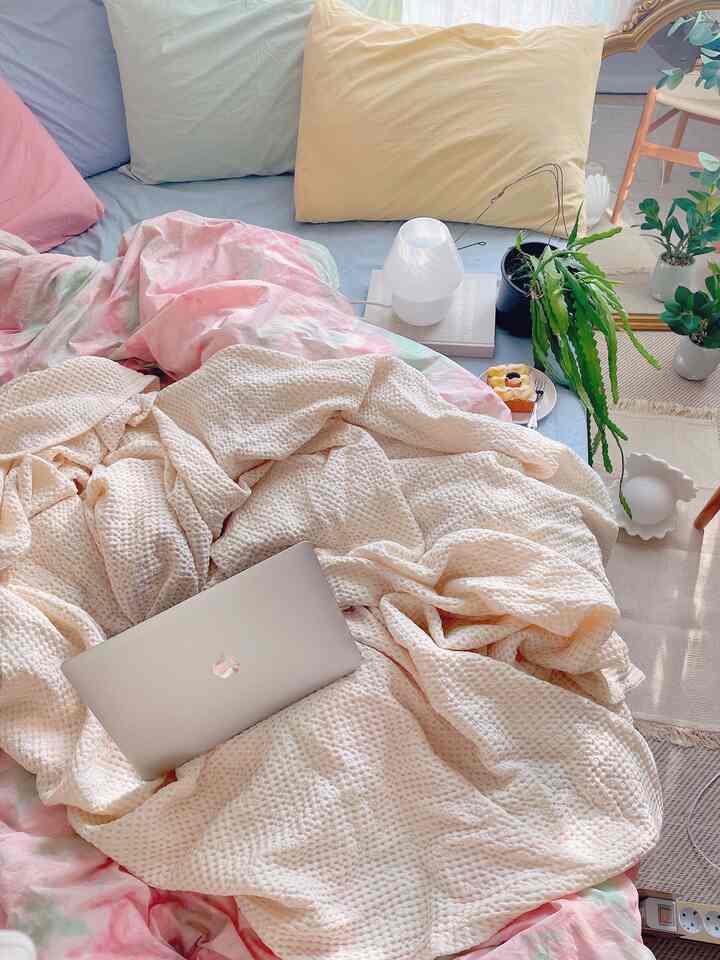 Pastel-toned bedroom featuring cozy bed with pillows and duvet cover alongside natural plants creating a calm atmosphere