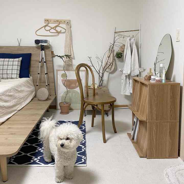 ナチュラルカラーとホワイトのトーンの寝室、木製ベッドとシンプルな化粧台が配置された実用的で暖かみのあるインテリア