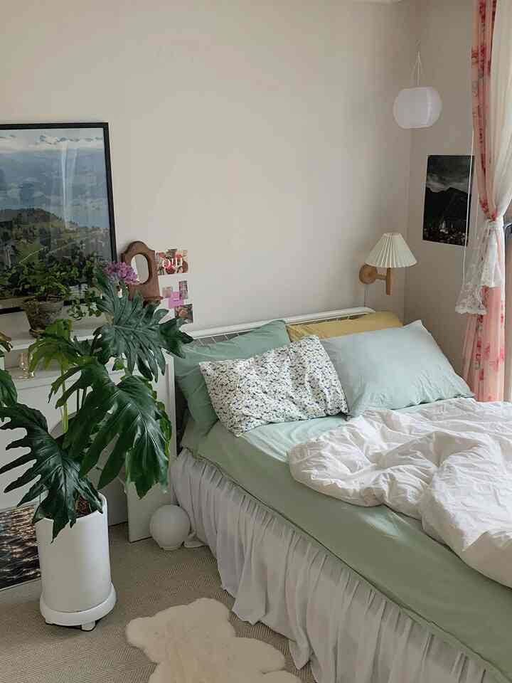 ホワイトとナチュラルトーンの寝室、グリーンプラントとホワイトの寝具が調和した落ち着いた空間