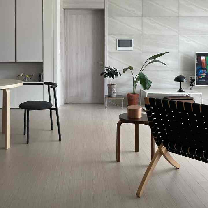 Natural-toned living room featuring lounge chair, coffee tables, and plants with modern, simple interior design